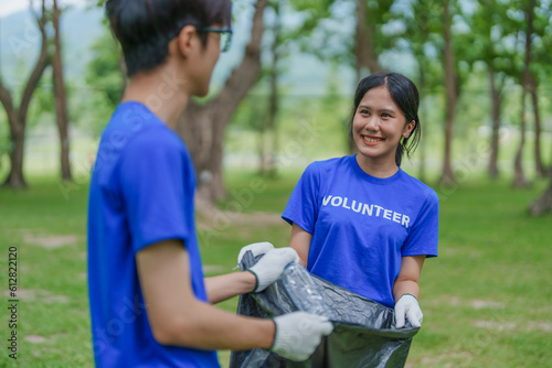 Multiethnic volunteers donate their time holding black garbage bags to collect plastic waste for recycling to reduce pollution in a public park.