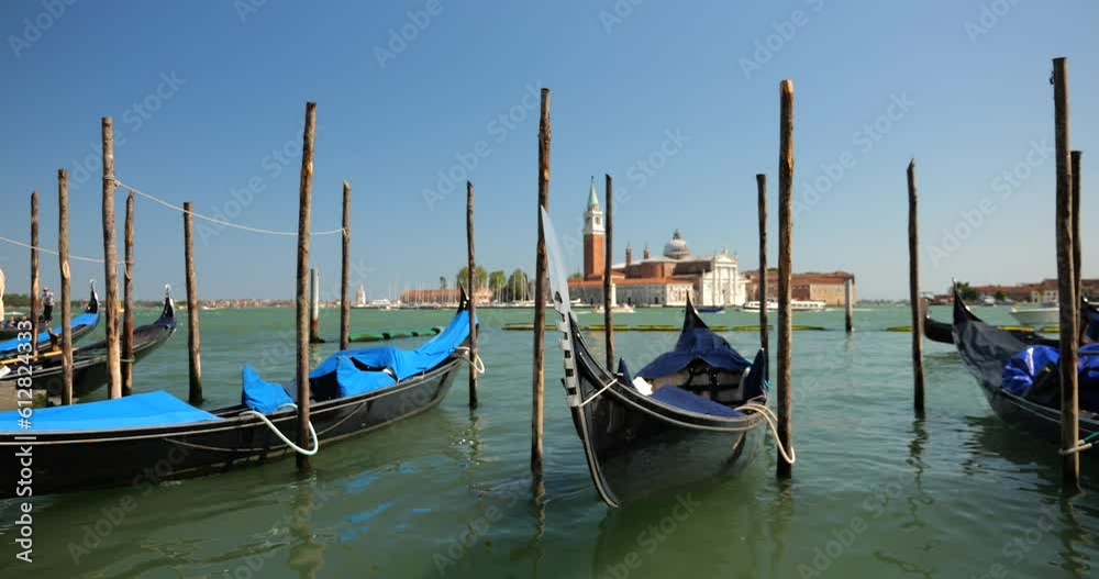 View from Riva degli Schiavoni on gondolas moored with palines in the Giudecca Canal and basilica San Giorgio Maggiore, opposite the Piazzetta di San Marco in Venice, Italy. View from Riva degli Schiavoni on gondolas moored with palines in the Giudecca Canal and basilica San Giorgio Maggiore, opposite the Piazzetta di San Marco in Venice, Italy.