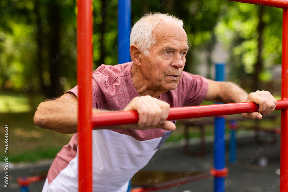 Fototapeta premium Mature man practice on the sports ground equipment in park