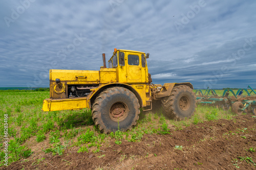 Spring photography  landscape with agricultural machinery  a tractor plows the land  plows a field  birds fly over arable land