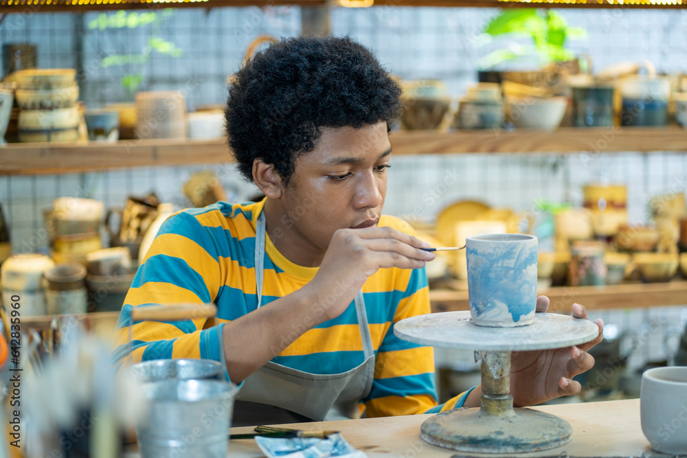 Craftsmanship at its finest, African american boy shaping clay into unique and elegant vases.