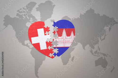 puzzle heart with the national flag of cambodia and switzerland on a world map background.Concept.