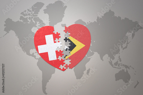 puzzle heart with the national flag of east timor and switzerland on a world map background.Concept.