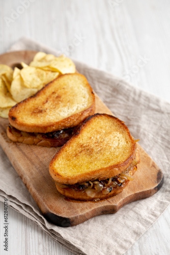 Homemade French Melt Sandwich with Caramelized Onion and Gruyure Cheese on a rustic wooden board, side view. Copy space.