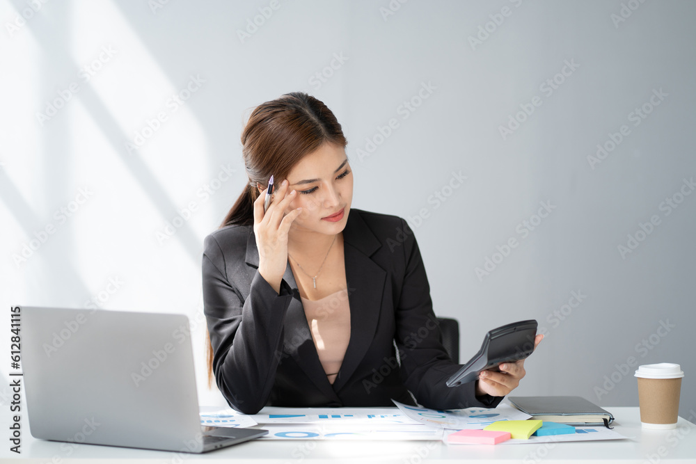 Young serious accountant working for her client, focusing on her work at office desk. Young serious accountant working for her client, focusing on her work at office desk.