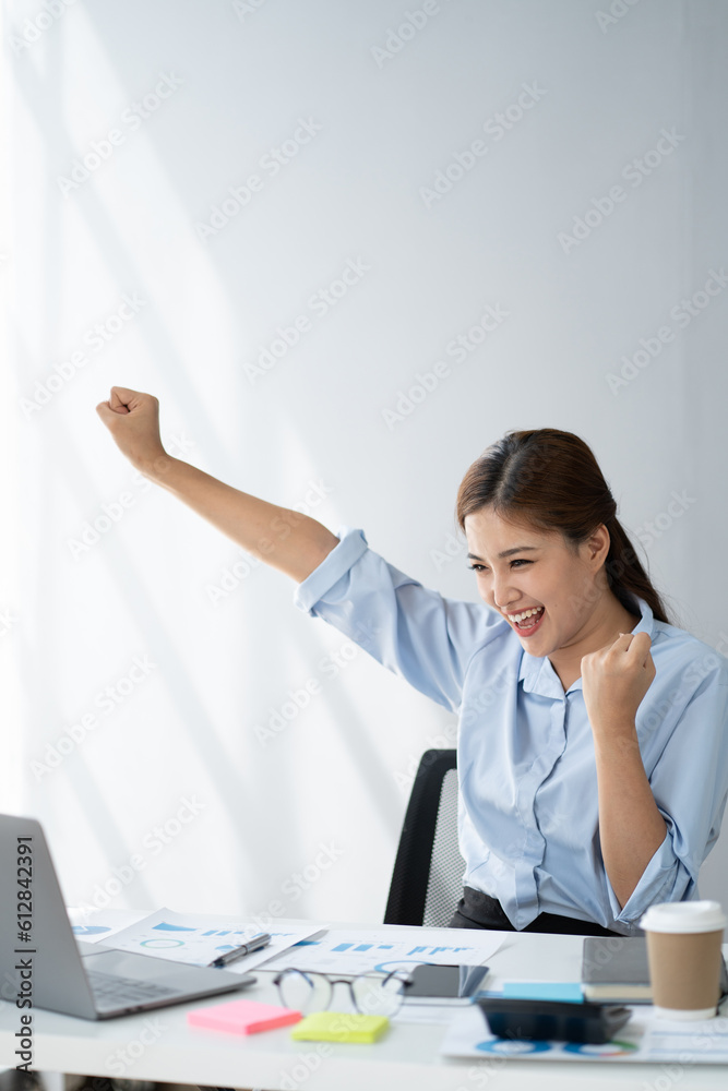 Cheerful young Asian business woman feeling overjoyed and celebrating after hearing the good news from her boss. Cheerful young Asian business woman feeling overjoyed and celebrating after hearing the good news from her boss.