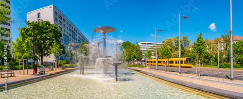 Dresden, Germany - Panoramic over fountain called Schalenbrunnen in Dresden with famous yellow tram. Cityscape of the downtown at sunny Spring day and blue sky.
