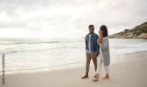 Εκτύπωση καμβά Smiling young multiethnic couple holding hands while walking on a sandy beach