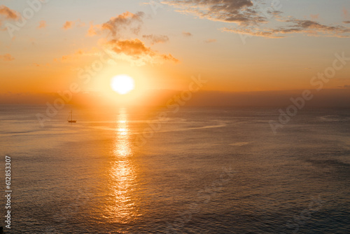Sunset against the backdrop of the ocean and yacht. Beautiful yellow sun sets over the sea