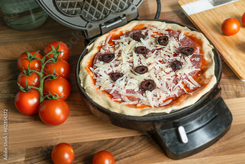 Fotografija Homemade pizza waffle with pepperoni, olives and parmesan cheese ready to bake i