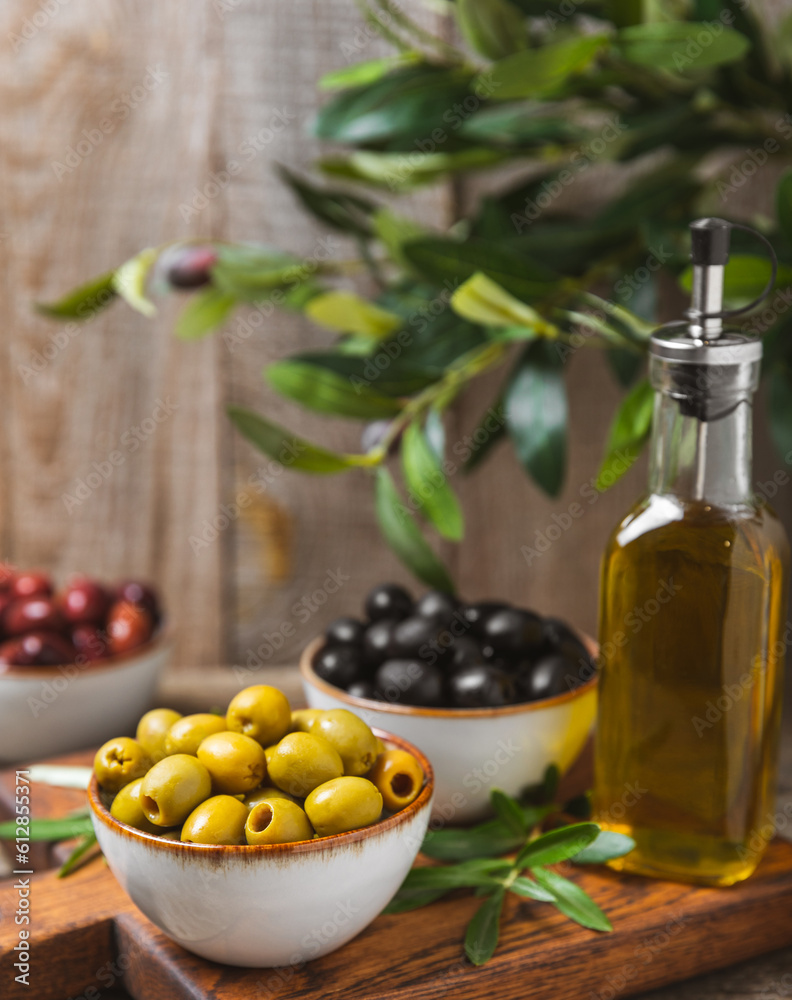 Green, black and red olives on a brown wooden background. Various types of olives in bowls and olive oil with fresh olive leaves. Copy space. Place for text. Mediterranean food. Vegan. Green, black and red olives on a brown wooden background. Various types of olives in bowls and olive oil with fresh olive leaves. Copy space. Place for text. Mediterranean food. Vegan.