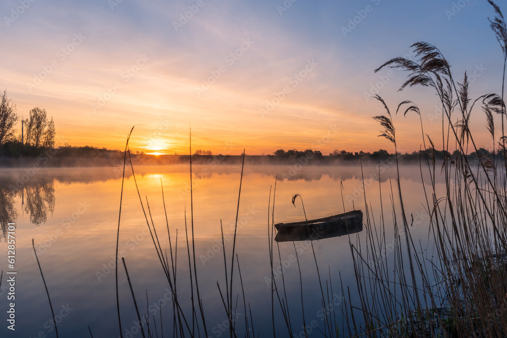 An old fishing boat on a lake during a beautiful sunrise