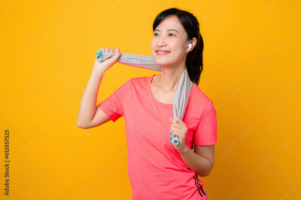 Portrait young asian sports fitness woman happy smile wearing pink sportswear and face towel doing exercise training workout against yellow studio background. wellbeing and healthy lifestyle concept. Portrait young asian sports fitness woman happy smile wearing pink sportswear and face towel doing exercise training workout against yellow studio background. wellbeing and healthy lifestyle concept.