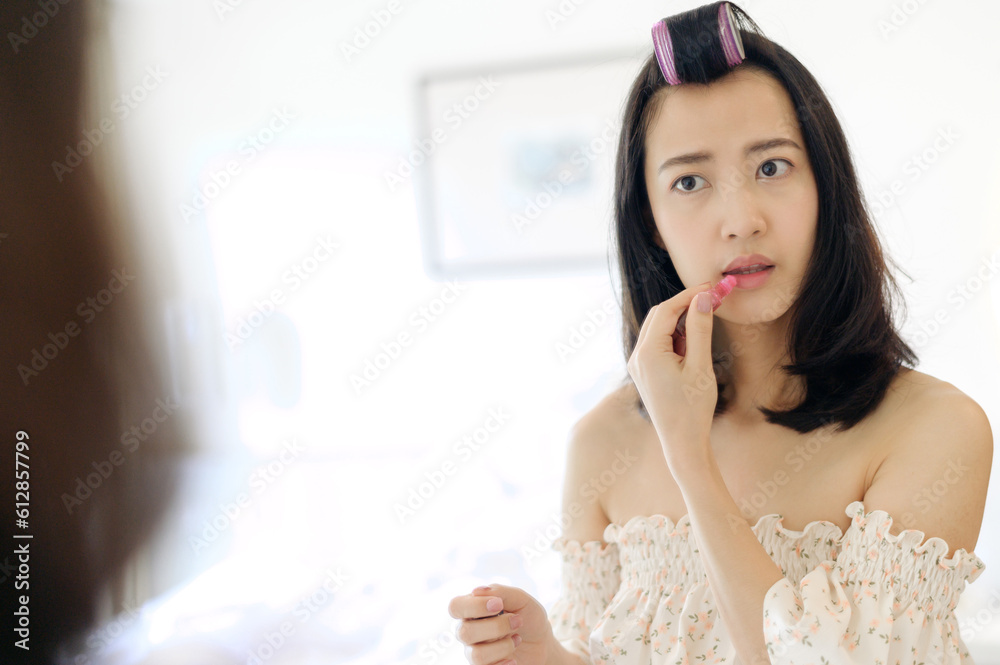 Beautiful young Asian woman applying makeup in front of the mirror. Lifestyle people concept. Advertisement for skin cream, anti-wrinkle cream, baby face Beautiful young Asian woman applying makeup in front of the mirror. Lifestyle people concept. Advertisement for skin cream, anti-wrinkle cream, baby face