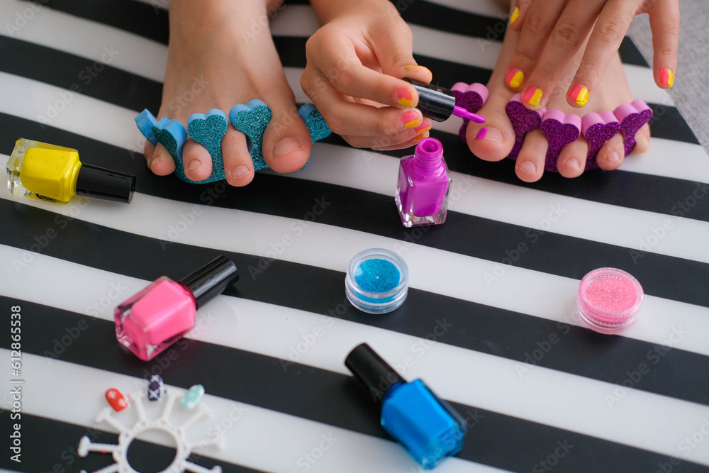 Children's feet with bright pedicure and manicure of different colors