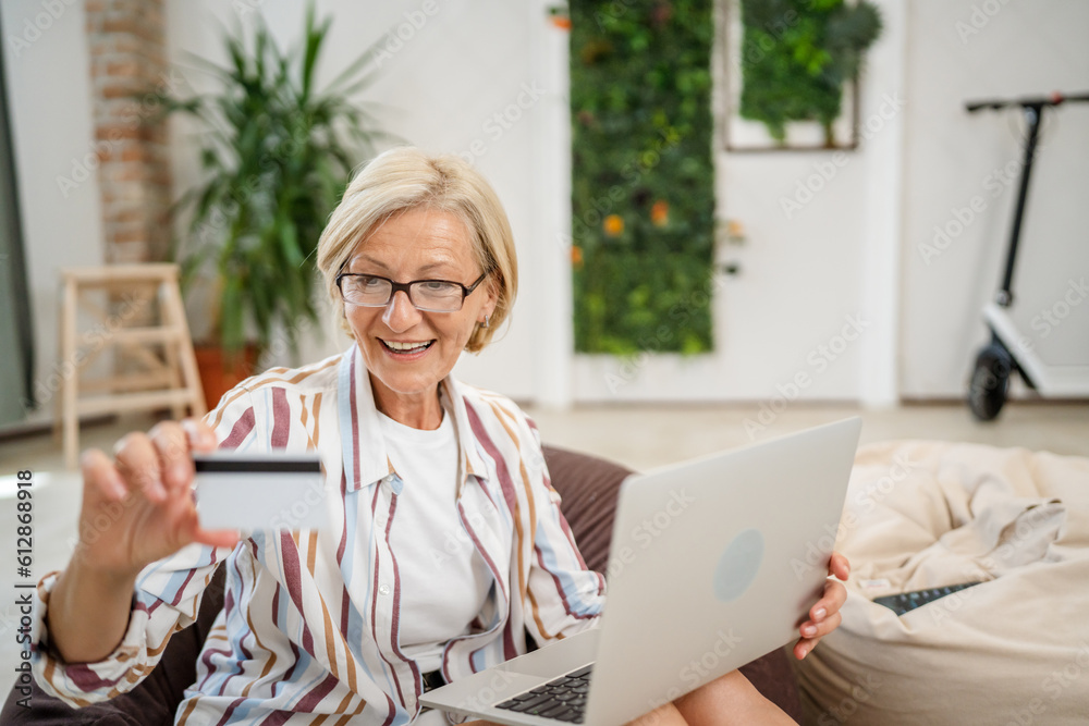 Mature caucasian woman shopping online hold credit card and laptop Mature caucasian woman shopping online hold credit card and laptop