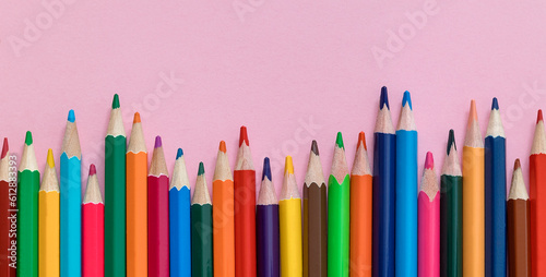 Colorful wooden pencilc crayons on a pink background. Top view. Copy space.