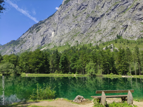A bench on a lake shore. Bluntausee  Austria. Mountain lakes. Alps. Blue crystal clear water. Summer rocky landscape. Hiking place. Green landscape. Lake coastline