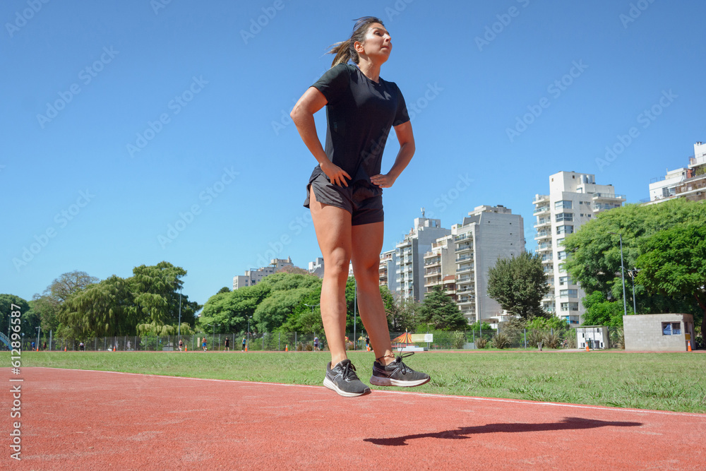 young latin woman runner training doing static jump with hand on waist