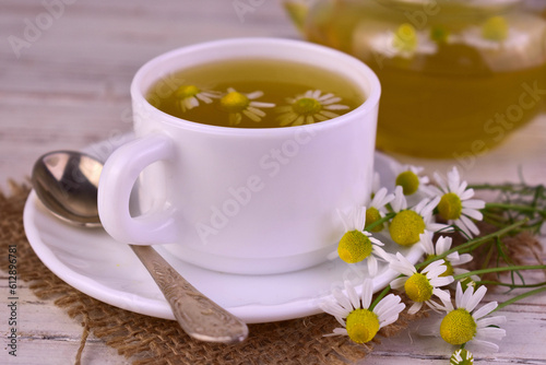 Medicinal chamomile tea in a cup on a white wooden background. 