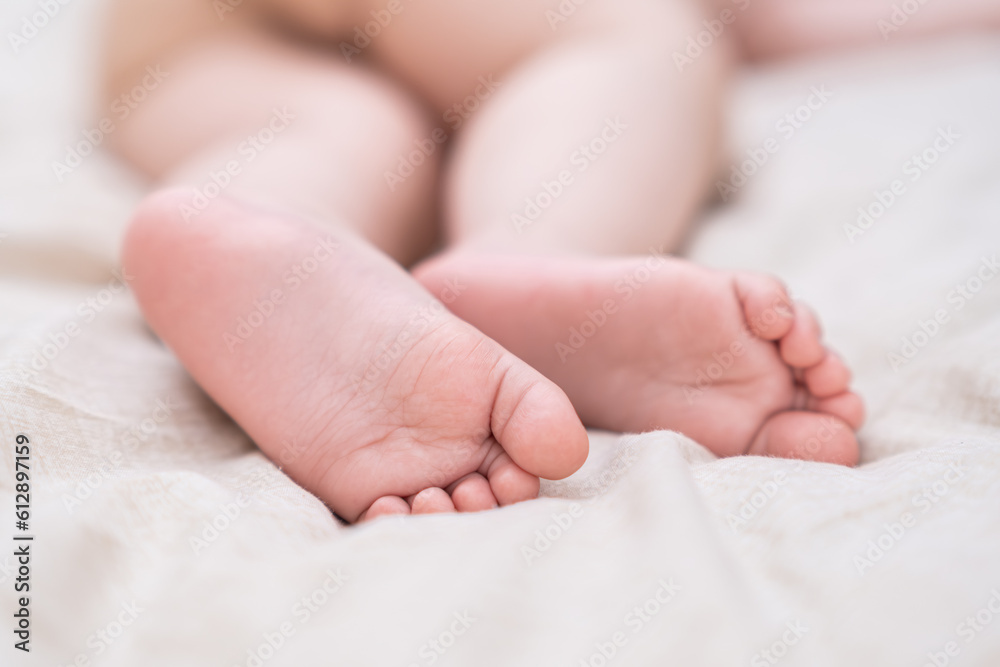 Cute wrinkled feet of infant baby with tiny toes lying on bed with soft white sheet barefoot little boy with tender skin sleeping in nursery in morning closeup Cute wrinkled feet of infant baby with tiny toes lying on bed with soft white sheet barefoot little boy with tender skin sleeping in nursery in morning closeup