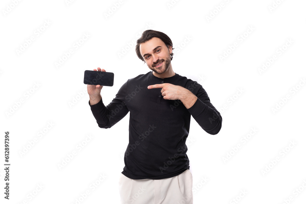 authentic brutal macho man with black hair and beard with an earring in his ear shows ads on the screen of a smartphone with a mockup on an isolated white background with copy space authentic brutal macho man with black hair and beard with an earring in his ear shows ads on the screen of a smartphone with a mockup on an isolated white background with copy space