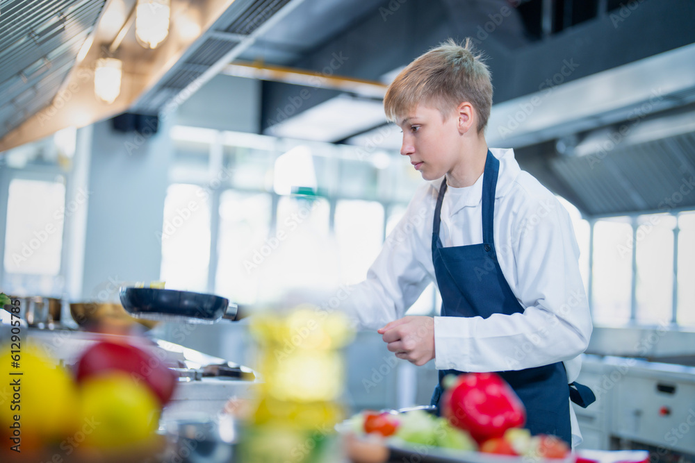 Young chef cooking at restaurant kitchen.