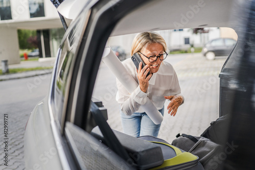 mature blonde woman travel take stuff belongings from the back of car © Miljan Živković