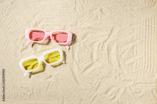 Stylish pink and yellow sunglasses on sand background at sunlight, summer fashion collection eyeglasses with colors glass. Summer sale concept. Top view lifestyle aesthetic photo, flat lay