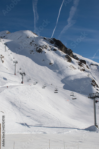 Ski resort in the mountains, with ski lifts, airplane vapor trails in blue sky, Les Deux Alpes, Isère, Auvergne-Rhône-Alpes, France
