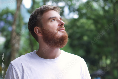 portrait happy handsome bearded young man in the park, guy sit on a bench and enjoy warm, fresh weather after the rain at summer