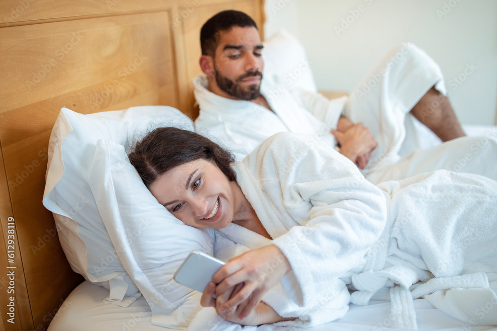 Suspicious husband seeing wife messaging on smartphone at home Suspicious husband seeing wife messaging on smartphone at home