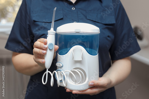 The dentist holds in hands a water oral irrigator for cleaning and hygiene of the dental cavity. No face.