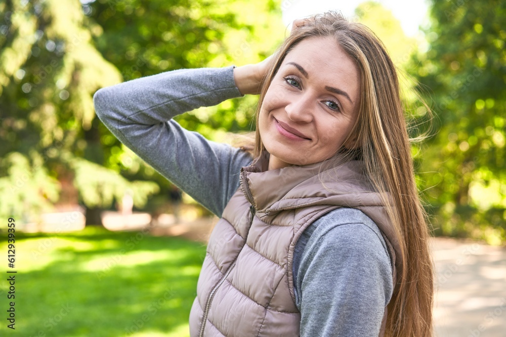 Joyful middle-aged woman, radiating happiness while posing in the park.