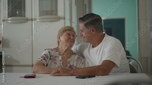 Candid Portrait of Middle-Aged Son and Elderly Mother in Domestic Kitchen Setting