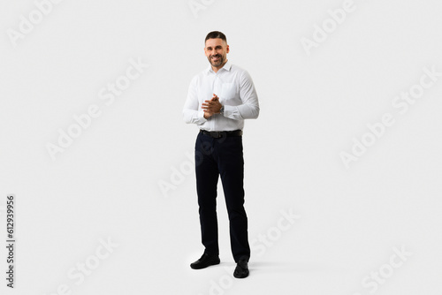 Full body length shot of handsome middle aged man entrepreneur in suit standing posing over light grey studio background