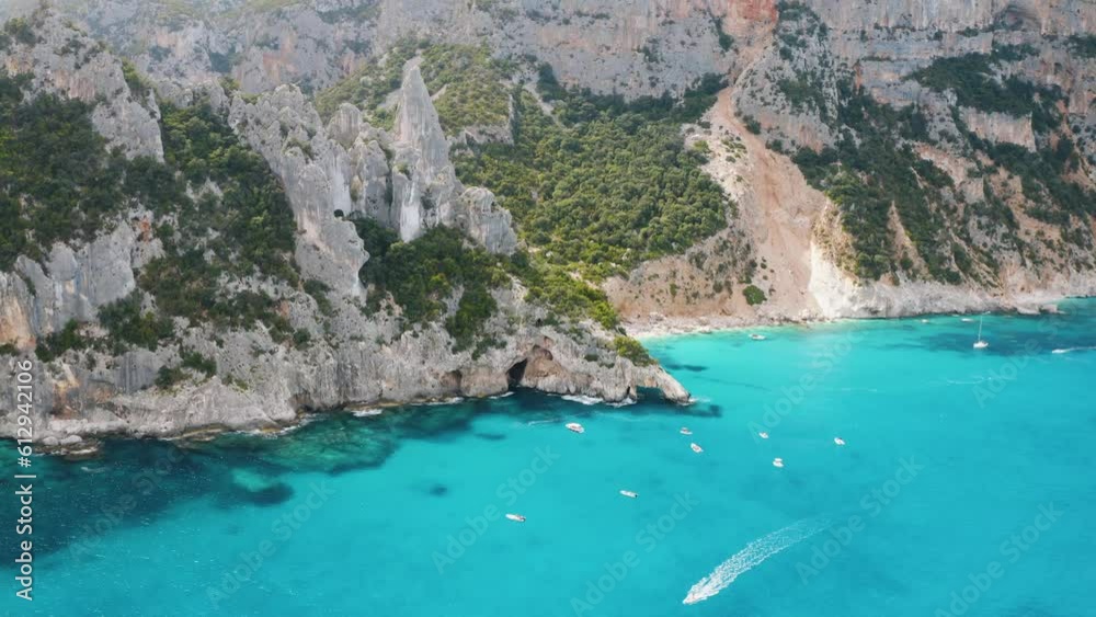 Aerial view of rocks and mountains, sea bay, beach, boats in summer day. Cala Goloritze, Sardinia Island, Italy. Top drone view of cliffs, stones, green trees, transparent azure water at sunset Aerial view of rocks and mountains, sea bay, beach, boats in summer day. Cala Goloritze, Sardinia Island, Italy. Top drone view of cliffs, stones, green trees, transparent azure water at sunset