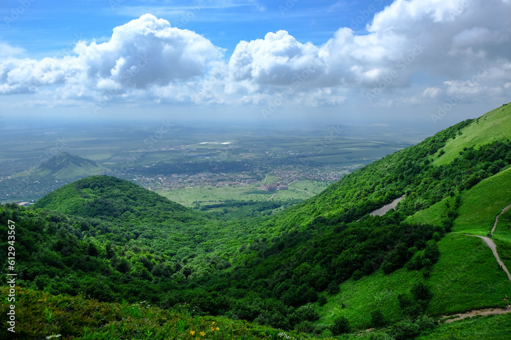 View of the green slopes of the mountains, the valley and the blue sky in the clouds