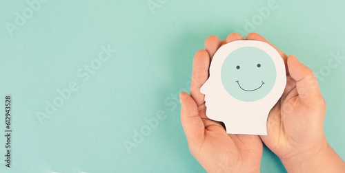 Holding a head with a happy smiling face in the hands, mental health concept, positive thinking, support and evaluation 