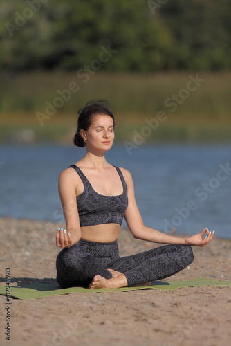 young naked woman practices yoga on the beach