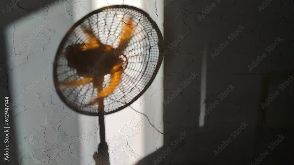 Primer plano de una sombra de un ventilador en movimiento en una pared con un fondo blanco.