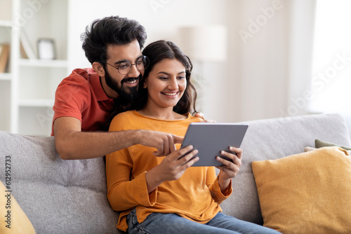 Technologies For Leisure. Happy Indian Spouses Relaxing With Digital Tablet At Home