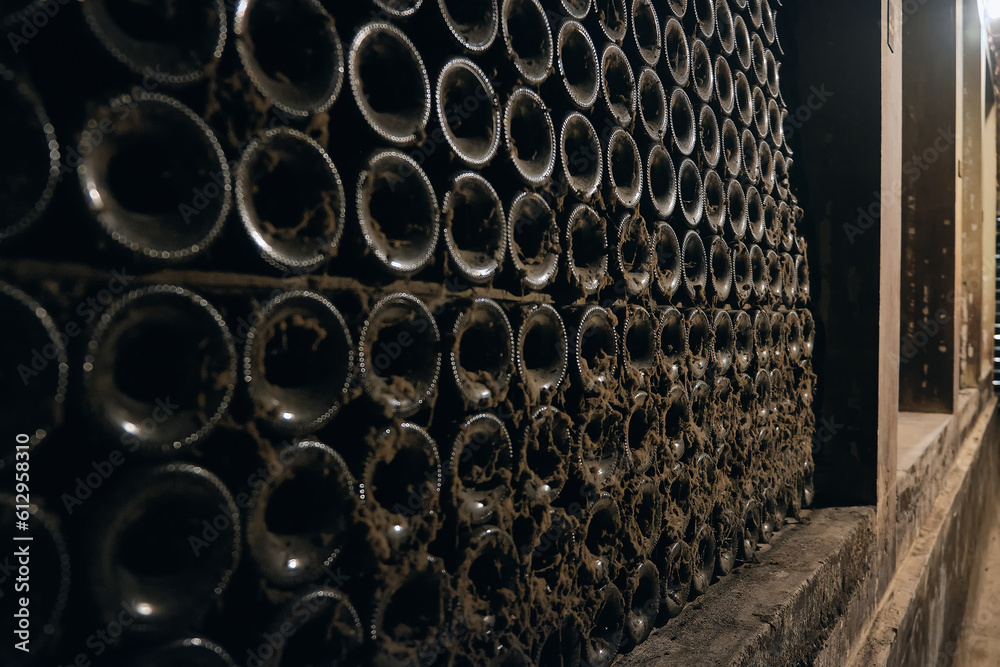 Stacked aged wine bottles covered with cobweb. Wine bottles in a bodega. Wine cellar in a cave. Bottles on a winery shelf covered by soft black mold Stacked aged wine bottles covered with cobweb. Wine bottles in a bodega. Wine cellar in a cave. Bottles on a winery shelf covered by soft black mold