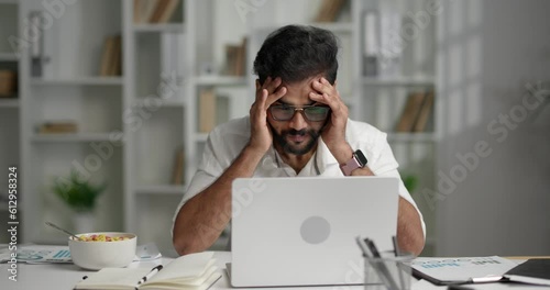 Stressed Indian man feeling tired and having a headache at work. 