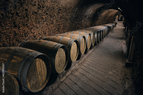 Row of wooden barrels bound with iron hoops in a bodega. Wine barrels made of oak at dark wine cellar. Wine cave at Beqaa valley  Lebanon