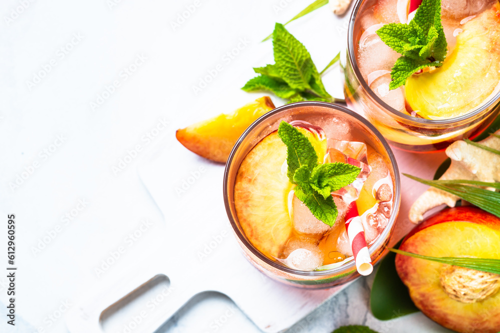 Peach cocktail, iced peach tea, fruit drink with tropical leaves. Top view with space for design. Peach cocktail, iced peach tea, fruit drink with tropical leaves. Top view with space for design.