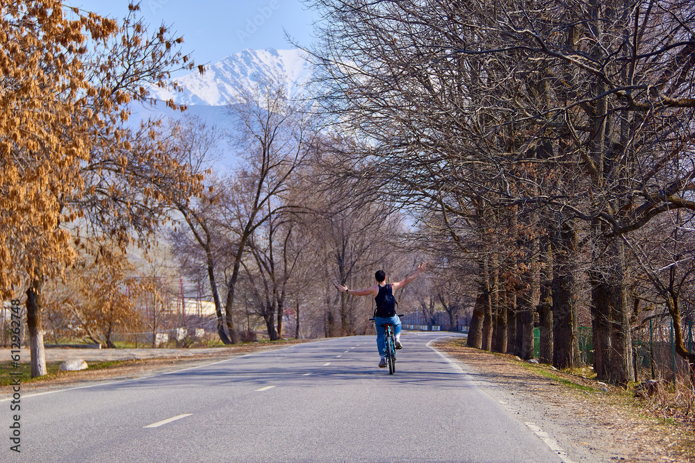 A cyclist on a bicycle goes down a mountain road. A fit and athletic man on a trip will be happy to spend time outdoors on a bicycle