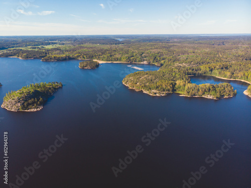 Aerial drone view of circle sea fish farm cages and round fishing nets, farming salmon, trout and cod, feeding the fish a forage, with Scandinavian lake landscape and forest island, a summer day