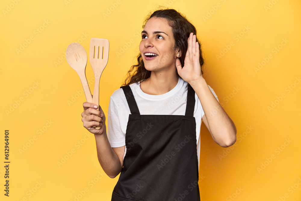 Woman with apron, wooden cooking utensils, yellow, trying to listening a gossip. Woman with apron, wooden cooking utensils, yellow, trying to listening a gossip.