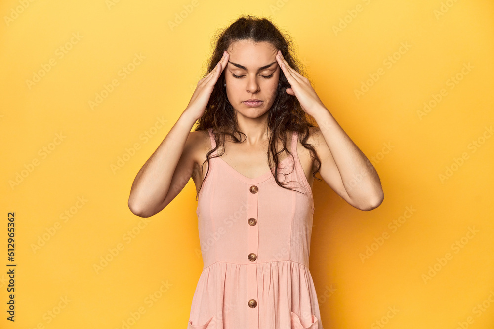 Young Caucasian woman, yellow studio background, touching temples and having headache. Young Caucasian woman, yellow studio background, touching temples and having headache.